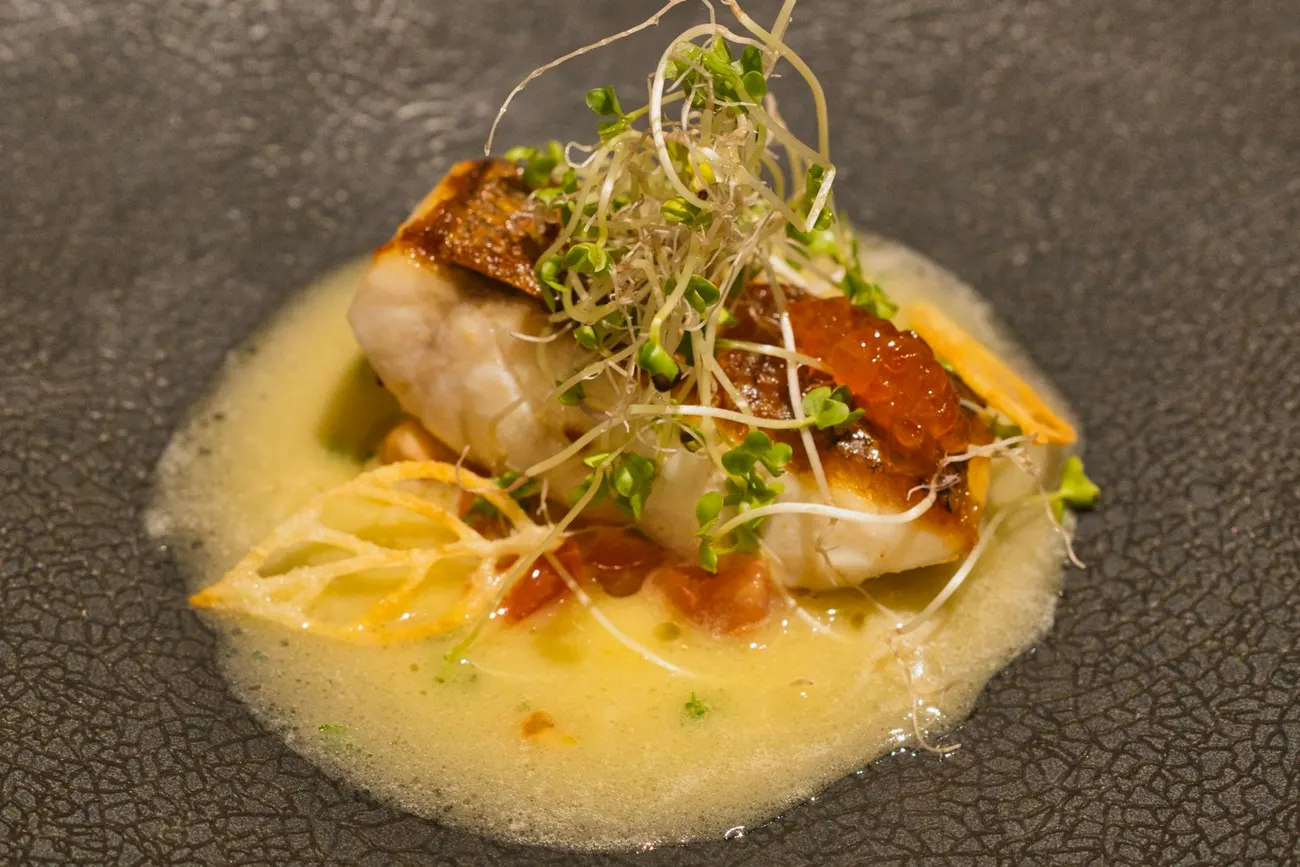 Crisp-skinned fish with vegetables and sauce on a ceramic plate