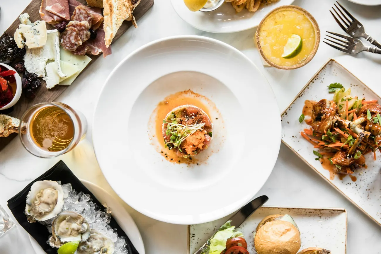 Several lunch plates and drinks laid out across a table